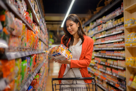 Woman selecting instant noodles in supermarket aisle