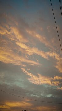 Vertical shot of a beautiful sunset sky with golden clouds and the silhouette of a utility pole and power lines in Japan