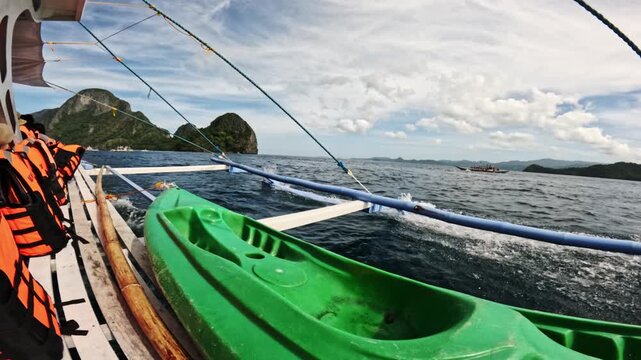 Kayaking scene in the Philippines featuring a green kayak and life jackets on a boat, with beautiful coastal landscapes and blue waters visible