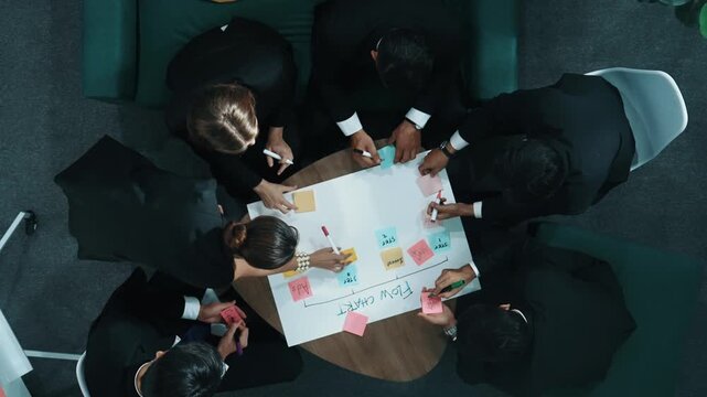 Top down view of business people hands making scrum task board to manage workflow in workplace. Diverse marketing team drawing a line and use colorful stick notes to work on kanban. Directorate.