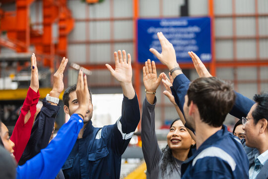 Diverse group of happy industrial factory warehouse worker raising hand together celebrating business success showing strong teamwork and cheerful motivation metal sheet factory