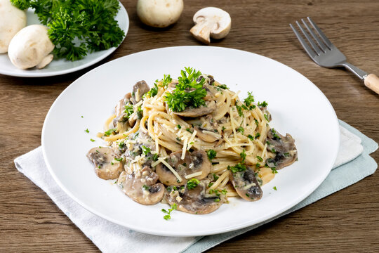 Spaghetti with champignon mushrooms and cream cheese on a wooden table