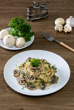 Spaghetti with champignon mushrooms and cream cheese on a wooden table