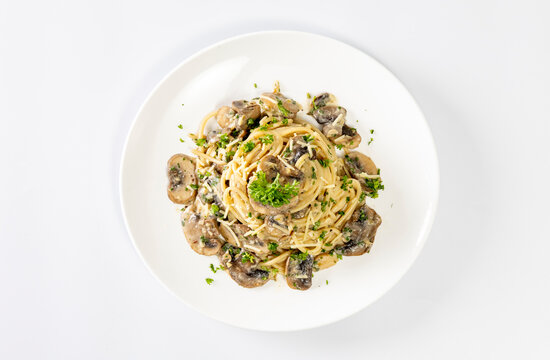 Spaghetti with champignon mushrooms and cream cheese on a white background.