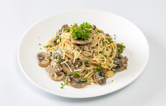 Spaghetti with champignon mushrooms and cream cheese on a white background.