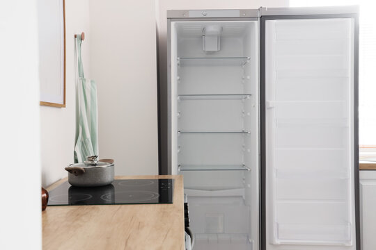 Empty open refrigerator with glass shelves in a modern kitchen, food storage and appliance