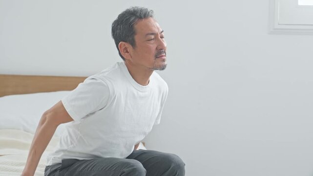 腰痛に悩むシニア男性。ぎっくり腰、ミドル、中高年、老化、加齢、痛み、困る、ヘルニア、ベッド、健康、痔