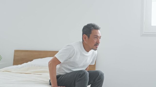 腰痛に悩むシニア男性。ぎっくり腰、ミドル、中高年、老化、加齢、痛み、困る、ヘルニア、ベッド、健康