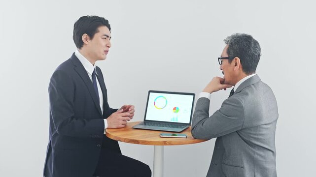 ノートPCを見ながら会話するビジネスパーソン。営業、提案、会議、打ち合わせ、マーケティング、人材