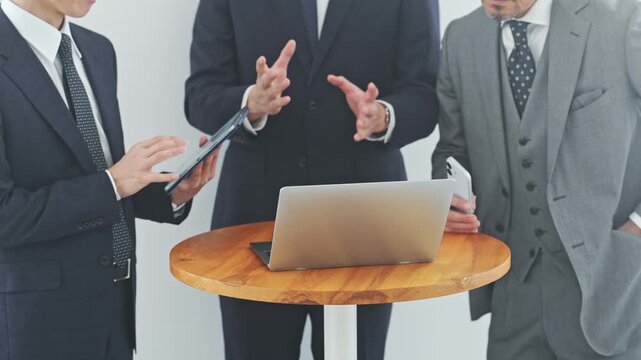ノートPCを見ながら会話するビジネスパーソン。会議、チームワーク、グループ、DX、IT、人材、会社