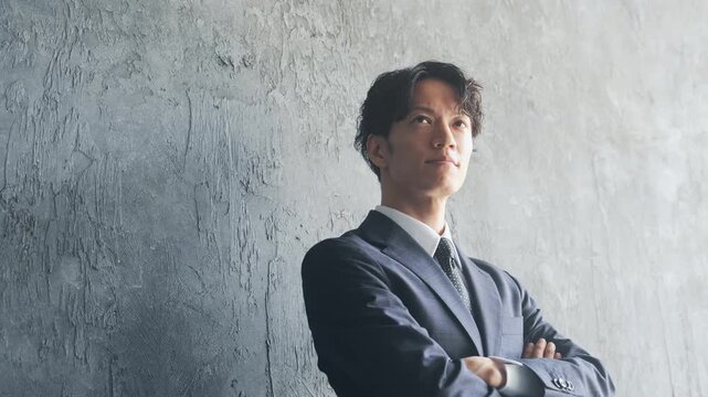 腕組みする男性ビジネスパーソン。目標、自信、見上げる、挑戦、チャレンジ、希望、サクセス、スーツ、覚悟