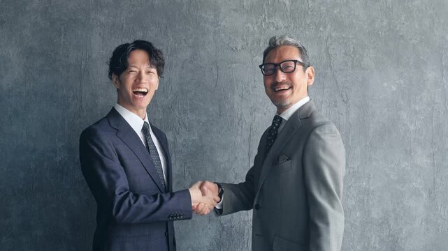 握手する男性ビジネスパーソン。チームワーク、協力、サポート、笑顔、事業承継、営業、契約、採用、人材