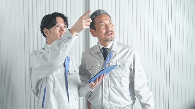 打ち合わせする男性作業員のグループ。建設、工事、工場、業者、相談、会議、DX、修理、点検、建築、内装