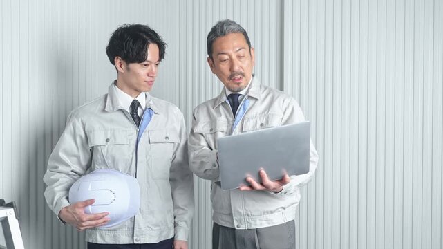 打ち合わせする男性作業員のグループ。建設、工事、工場、業者、相談、会議、DX、修理、点検、建築、内装