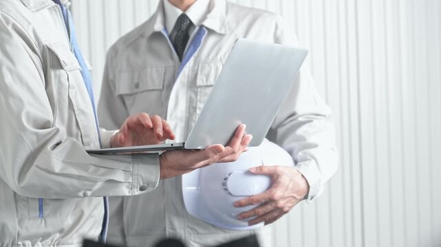 打ち合わせする男性作業員のグループ。建設、工事、工場、業者、相談、会議、DX、修理、点検、建築、内装