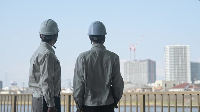 建設中の都市を眺める男性作業員のグループ。工事、チームワーク、安全、点検、建築、現場、ビルメン、検査