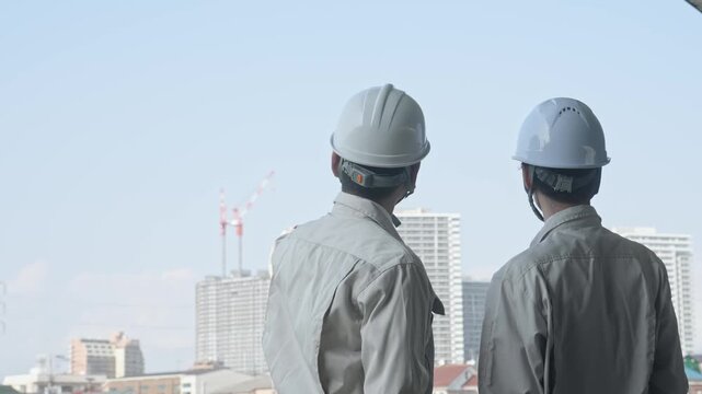 建設中の都市を眺める男性作業員のグループ。工事、チームワーク、安全、点検、建築、現場、ビルメン、検査