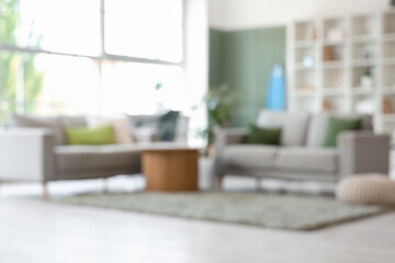 Fototapeta premium Interior of stylish modern living room with surfboard and sofas, blurred view