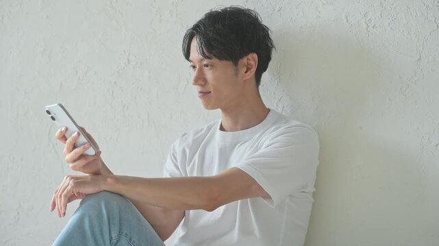 スマホを使う男性。アプリ、SNS、動画、メール、DX、ゲーム、リラックス、若者、検索、スマートフォン