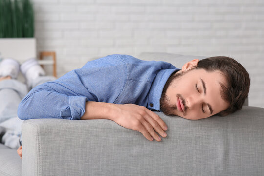 Tired young man sleeping on couch at home