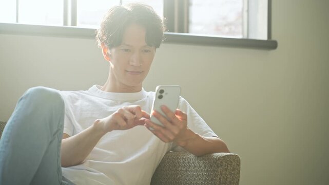 スマホを使う男性。アプリ、SNS、動画、メール、DX、ゲーム、リラックス、若者、検索、スマートフォン