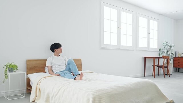 寝室でくつろぐ男性。リラックス、ベッド、目覚め、朝、起床、あくび、健康、若い、爽やか、ホテル、宿泊