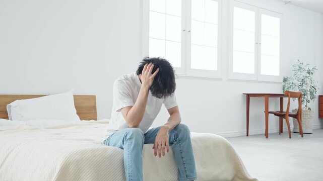 寝室で悩む男性。疲労、肩こり、つらい、落ち込む、失敗、困る、ストレス、がっかり、不満、ホテル、宿泊
