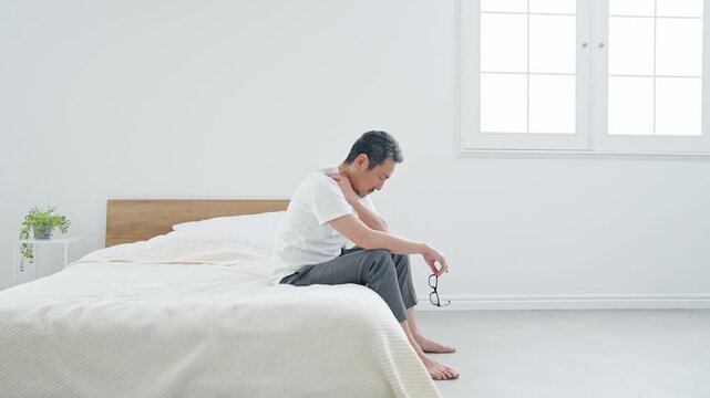 肩こりに悩むシニア男性。疲労、疲れ、ベッド、ミドル、中高年、ストレス、加齢、老化、落ち込む、がっかり