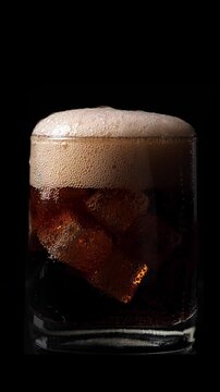 Pouring soda water into the glass. Closeup. Black background. Vertical footage
