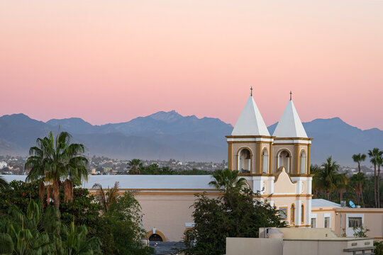 bell towers of mission san jose church and mountains on horizon overlooking city of san jose del cabo mexico