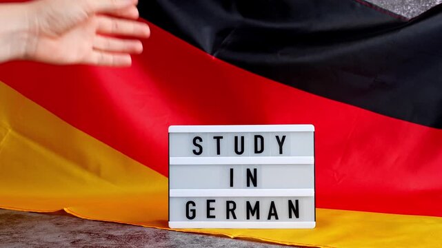 Lightbox with text STUDY IN GERMAN National symbol of Germany. German wave silky flag background. Concept of education and learning 
