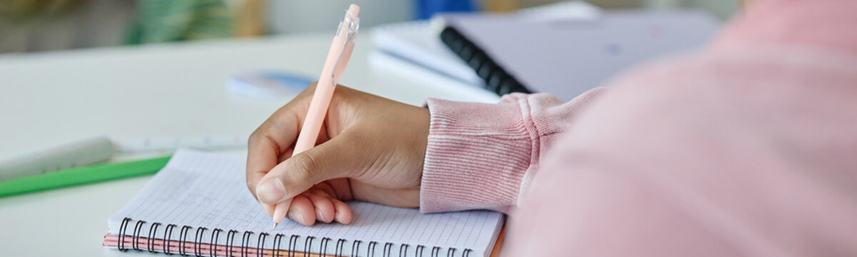 Close up of child hand writing in notebook during lesson, showing learning focus and school study routine. Useful for education marketing, tutoring services, academic content
