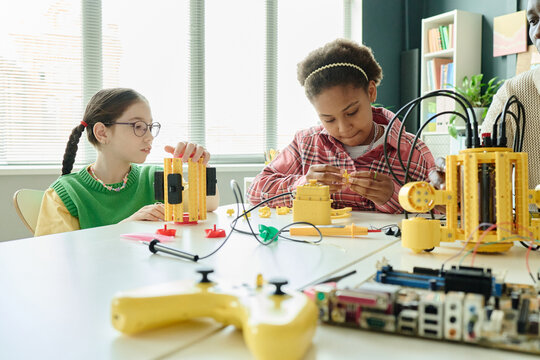 Schoolgirls assembling robotics project during STEM class, learning engineering and coding through hands on teamwork. Ideal for education marketing, youth innovation, technology programs