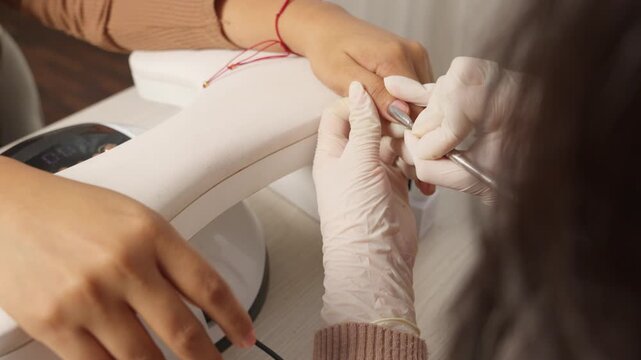 Professional manicurist pushing cuticles during beauty salon manicure procedure