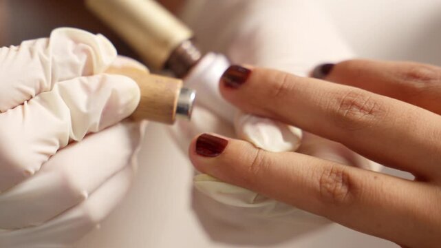 Professional manicurist applying cuticle oil during manicure treatment