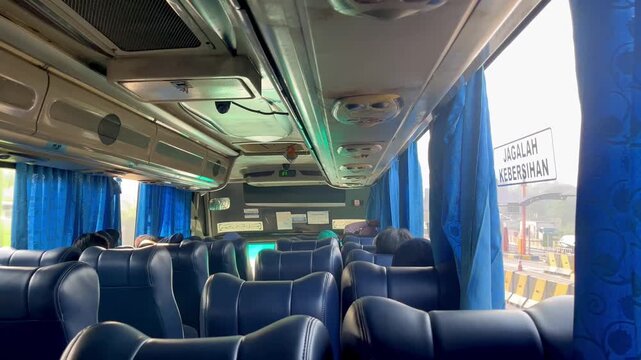 Modern bus interior with blue-themed cabin design and several passengers seated during a public transportation journey. Clean, comfortable, and spacious urban transit environment suitable for travel, 