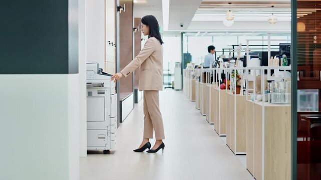 Young Asian Businesswoman Printing Documents with Office Copier in Modern Workplace