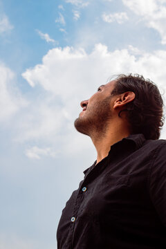 Smiling young man looking up at the blue sky
