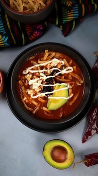 Mexican food, Aztec soup or sopa azteca, a classic Mexican dish with tomato broth, cheese and pasilla chili. Camera rotating slowly
