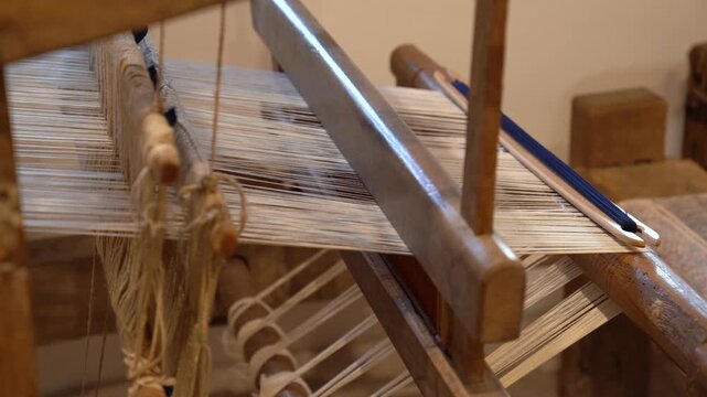 Traditional old weaving loom with white yarn and a blue shuttle
