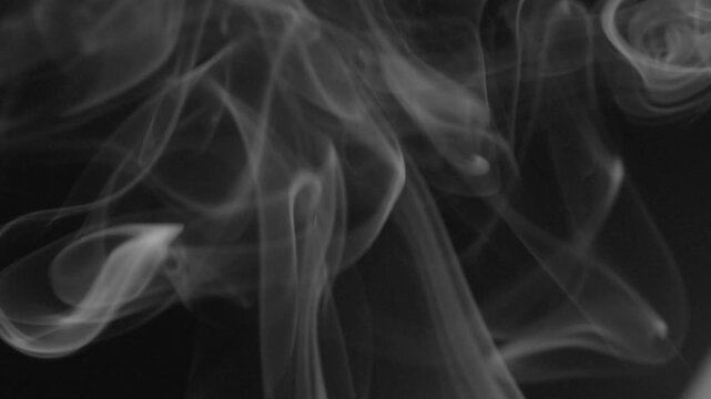 Macro view of swirling incense smoke forming abstract shapes against dark background, highlighting fluid movement, translucent layers, and drifting patterns.