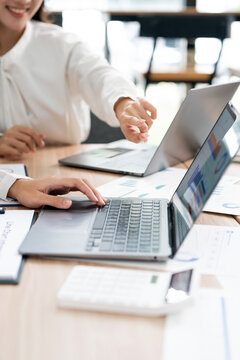 Close up of business people working together on laptops in office meeting, vertical orientation.