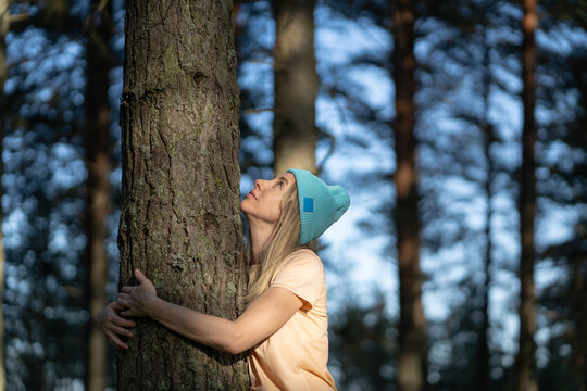 Positive calm woman hugs tree trunk in woods, practicing forest bathing known as Japanese shinrin yoku therapy, female hiker nature lover embracing tree in woodlands, mindfulness and mental relaxation