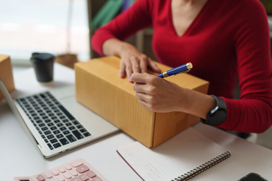 Woman writing on a shipping box for online business delivery