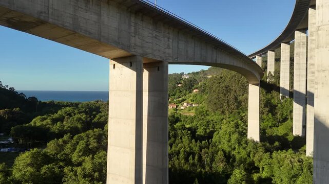 Drone view under the La Concha de Artedo viaduct above forest and sea