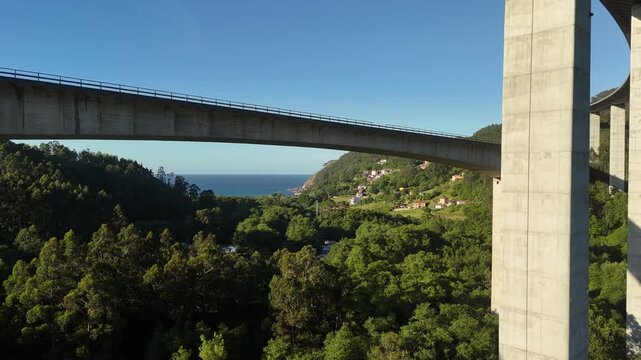 Drone view under La Concha de Artedo viaduct with sea and forest below