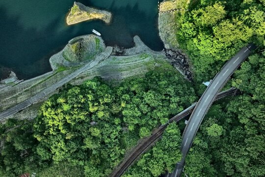 Aerial drone photo of Nagashima Dam shoreline with railway and road, Oigawa, Japan