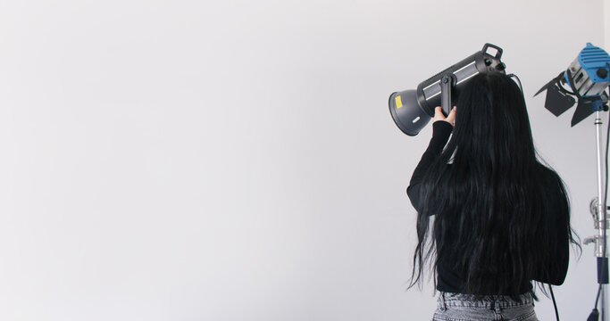 Professional light. Studio workflow. Female photographer preparing for creative occupation using equipment at modern workplace.
