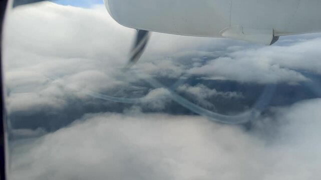 Aerial view from propeller airplane window flying through clouds in Fiji, South Pacific