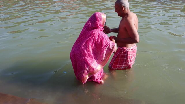 old age couple Devotees helping each other for Holy Dip in Sacred River During Religious Pilgrimage